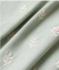 Close-up of sage green cotton with scattered white floral embroidery