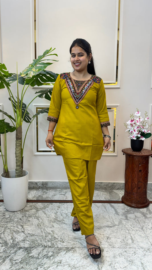 Woman wearing a mustard yellow short kurti with mirror work embroidered yoke and matching straight palazzo