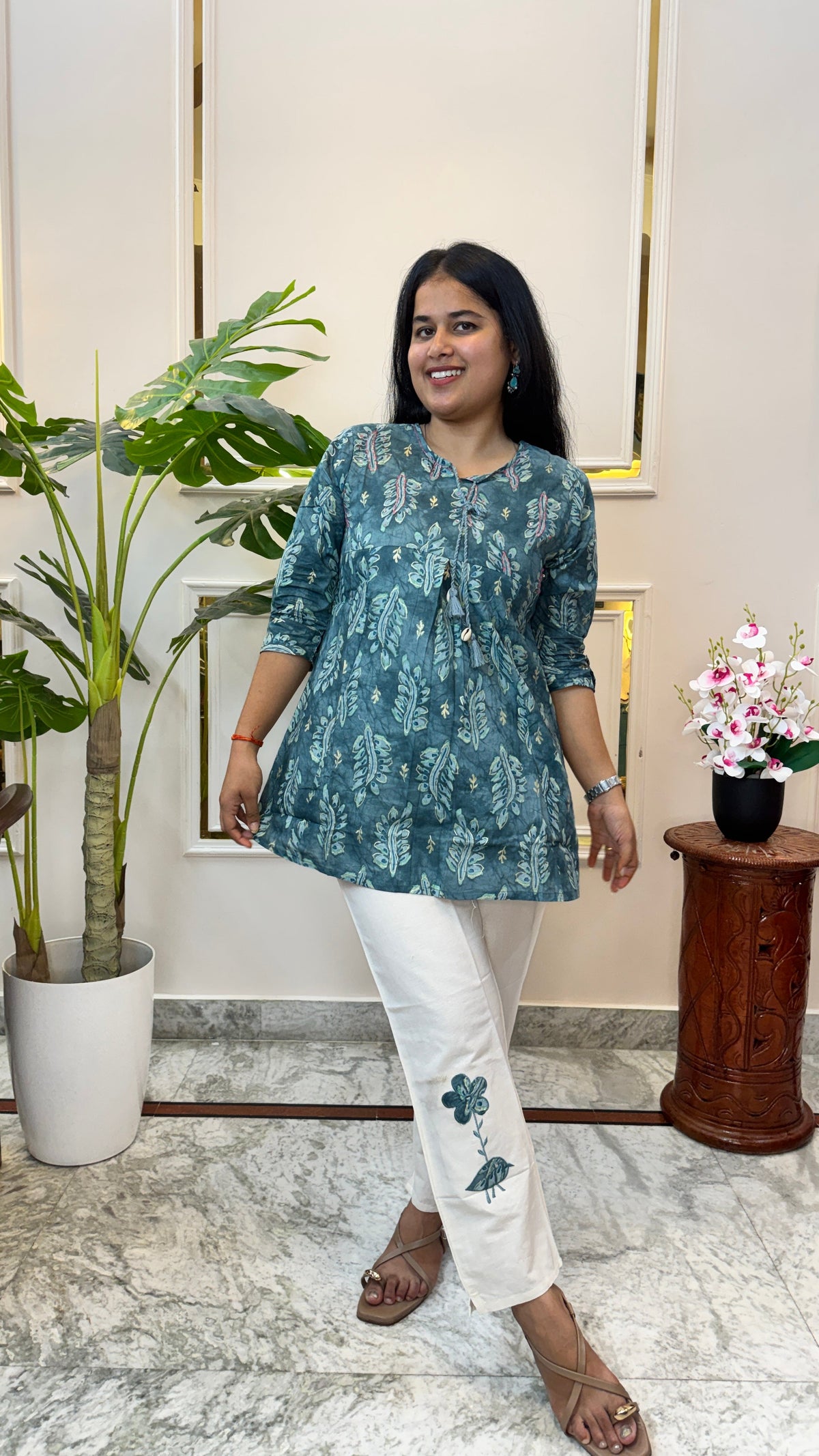 Woman wearing a teal blue batik print A-line kurti with off-white straight pants