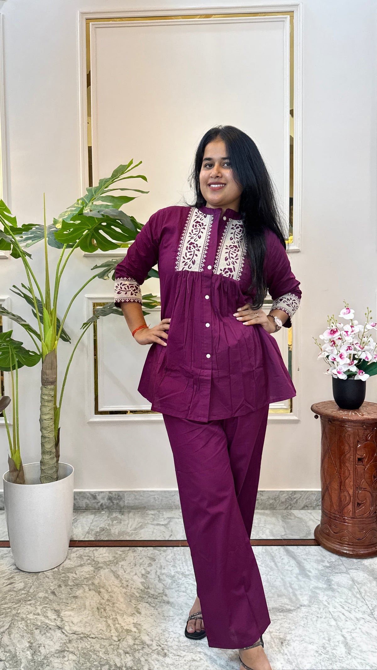 Woman wearing a wine purple A-line kurti with cream floral print yoke and matching palazzo